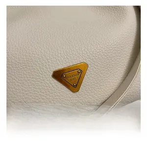 Macro view of lychee texture leather and inverted triangle gold metal logo hardware