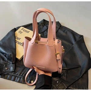 Close-up of pink litchi grain leather bucket bag with gold hardware and strap