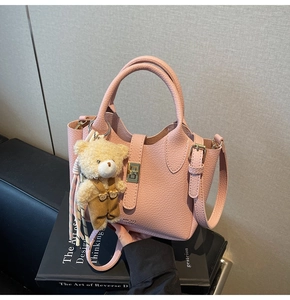 Dettaglio borsa in pelle rosa con chiusura in metallo e ciondolo a forma di orso