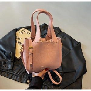Detail of pink lychee leather bucket bag with top handles and adjustable strap