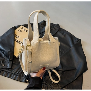 Detail of cream bucket bag showing lychee grain leather texture and gold hardware