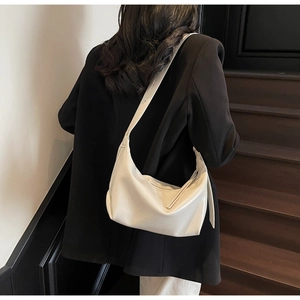 Detail shot of a cream crescent shoulder bag featuring a smooth PU leather finish