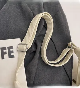 Close-up of adjustable cream PU leather shoulder strap with silver metal buckle detail