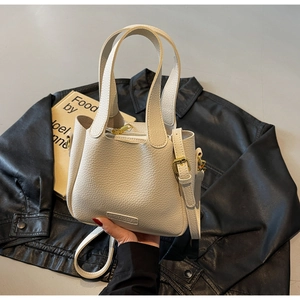 Detail of off-white lychee grain leather handbag with gold hardware and logo embossing