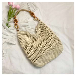 Détail du sac fourre-tout beige au crochet avec texture ajourée et anses en perles de bois