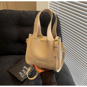Detail of off-white lychee texture bucket bag with gold hardware and brand tag