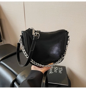 Detail of black saddle bag with silver chain strap and smooth leather texture
