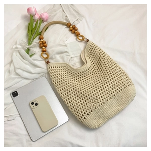 Détail du sac cabas tissé beige avec bandoulières en perles de bois naturel et maille ajourée