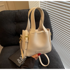 Detail of beige bucket bag with lychee texture, golden hardware and CHERIMATA logo