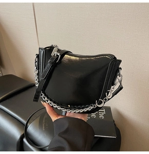 Detail of glossy black moon saddle bag with silver chain and moon-shaped pendants