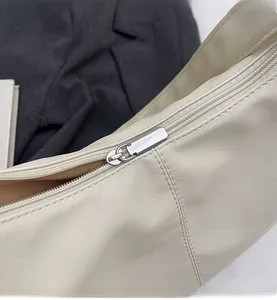 Detail of smooth silver metal zipper and soft cream PU leather texture on tote bag