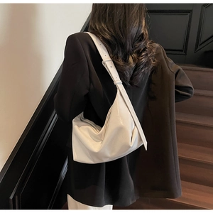 Detail of white glossy leather crescent bag showing natural folds and zipper closure