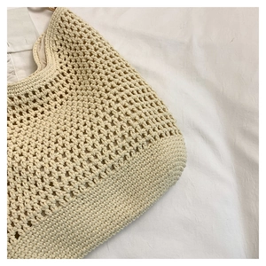 Gros plan d'un sac de plage en crochet beige fait main avec des motifs ajourés et boucles