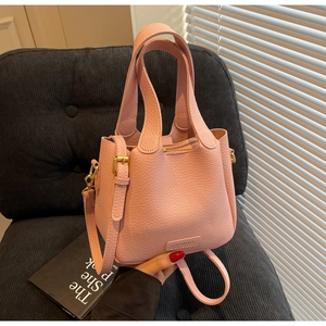 Close-up of pink litchi grain leather bucket bag with brand logo and gold buckle hardware