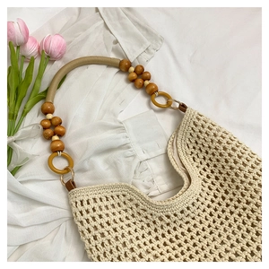 Détail du sac de plage crocheté avec texture beige et poignée décorative en perles de bois