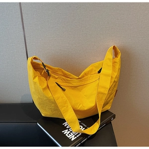 Detail of yellow nylon tote bag featuring wide adjustable strap and sleek black buckle