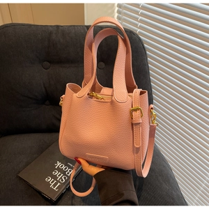 Close-up of pink lychee grain bucket bag with gold hardware and wide top handles