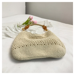 Texture détaillée du sac fourre-tout tissé crème avec des perles en bois brun foncé sur l'anse