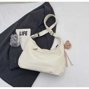 Detail of off-white leather hobo bag with adjustable strap and cute bear charm accessory