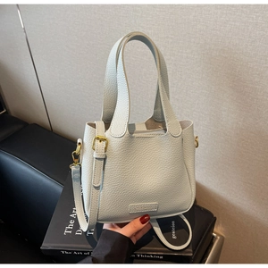 Detail of light blue lychee pattern leather bucket bag with golden hardware and metal logo