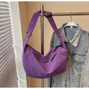 Detail of purple nylon crescent tote bag showing smooth fabric texture and wide shoulder strap