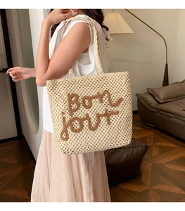 Dettaglio della borsa tote intrecciata con ricamo Bonjour e trama in maglia di paglia