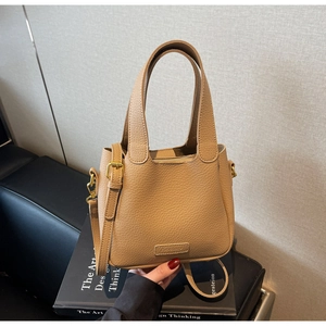 Detail of lychee textured leather bucket bag with reinforced handle and golden hardware