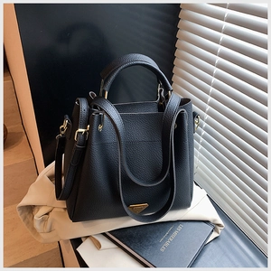 Detail of black lychee grain leather bucket bag with gold hardware and shoulder strap