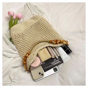 Détail d'un sac cabas tissé main avec anse en perles de bois et produits de beauté