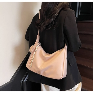 Side view of soft apricot pink leather hobo bag with plush charm and wide strap detail
