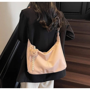Detail of pink PU leather tote bag with brown plush bear charm and woven cord decoration