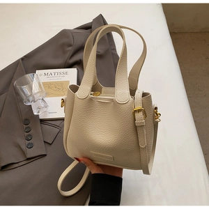 Detailed macro of creamy white litchi grain leather bucket bag with gold hardware