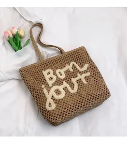 Dettaglio della borsa tote in paglia intrecciata a mano con ricamo Bon jour su tessuto