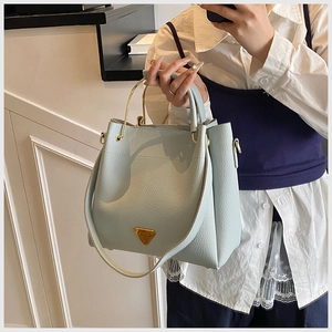 Macro shot of mint green lychee grain leather bucket bag with gold triangular metal logo
