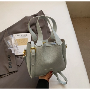 Detail of light blue lychee pattern leather bucket bag with gold hardware and branding