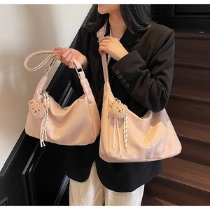Detail of light pink Hobo bag with soft PU leather texture and plush bear charm