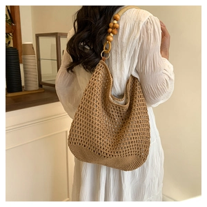 Gros plan d'un sac cabas au crochet marron avec des perles en bois sur la bandoulière