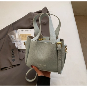 Detail of mint green lychee pattern leather bucket bag with gold hardware and embossed logo
