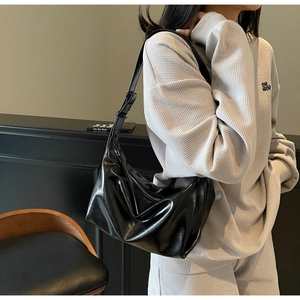 Detail view of glossy black crescent shoulder bag with adjustable strap and metal buckle