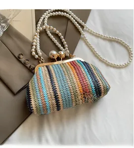 Detail view of a colorful woven handbag featuring an oversized pearl clasp and long chain