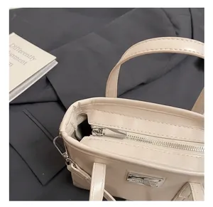 Detailansicht beige Leder Eimertasche mit Silber-Reißverschluss und glänzendem Metall-Logo