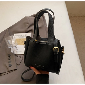Detail of black lychee grain leather bucket bag with gold hardware and top handles