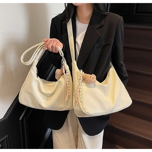 Detail of soft cream faux leather hobo bags with cute brown bear and tassel charm accessories