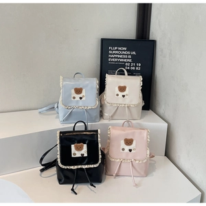 Detail of four colorful mini backpacks with lace trim and plush bear charms