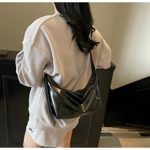 Close-up of black glossy hobo bag worn with a grey waffle knit casual lounge set