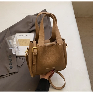Detail of light brown lychee grain leather bucket bag with gold ring and adjustable strap