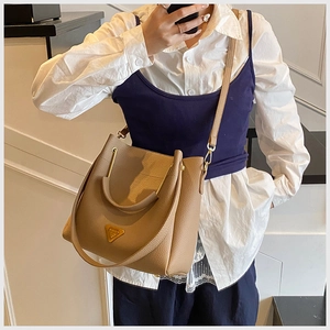 Detail of khaki litchi grain leather bucket bag with gold triangle logo and strap