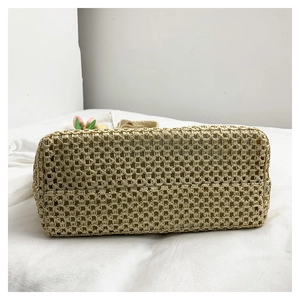 Detail of the rectangular bottom showing dense hand-woven texture on a beige straw beach bag