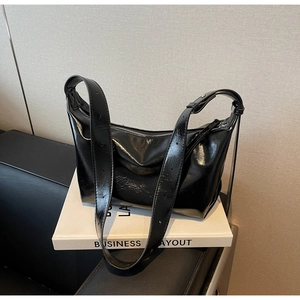 Close-up of black glossy hobo bag with adjustable wide strap and silver metal zipper