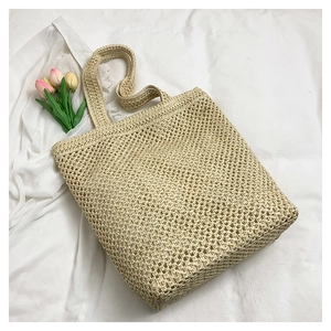 Close-up of beige crochet tote bag with hollow mesh design and floral background